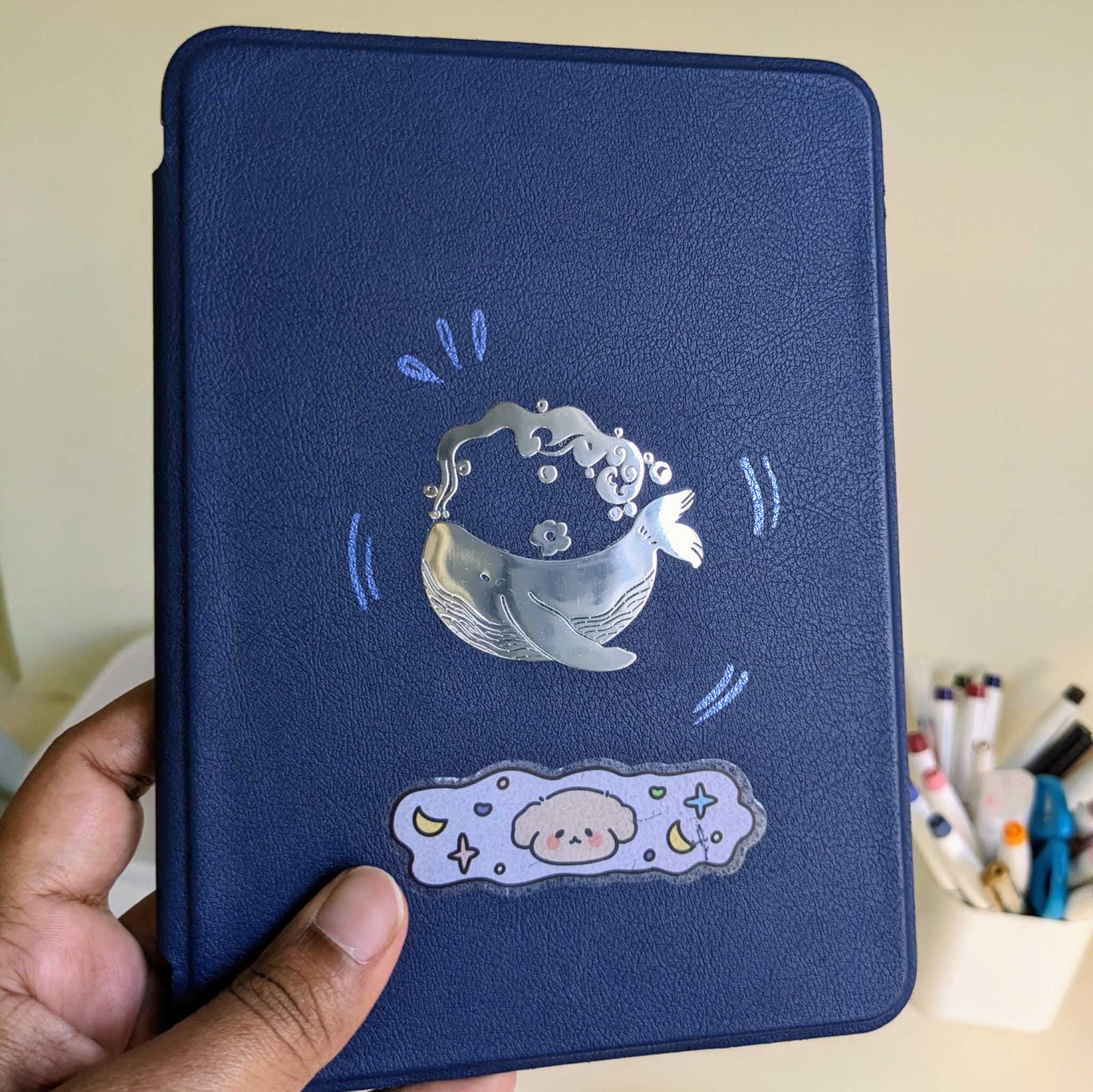 Silver metallic transfer sticker of a minimalist whale silhouette, featuring a raised 3D texture on a dark laptop surface