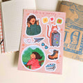 Sticker sheet featuring a girl making a victory sign, a girl on a balcony looking at trees, and a cat with a suitcase.